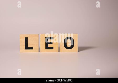 Der beliebte und moderne Name LEO für kleine Jungen in englischer Holzsprache Großbuchstaben, die aus einem Stapel von Buchstaben auf grünem Hintergrund in Sepia auslaufen Stockfoto