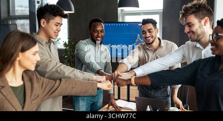Verschiedene Geschäftsleute, die im Büro einen Faustschlag im Kreis geben Stockfoto