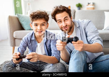 Gemütliches Familienwochenende. Überglücklich Vater und Sohn im Wettbewerb in Online-Videospielen, verbringen Zeit zusammen zu Hause Stockfoto