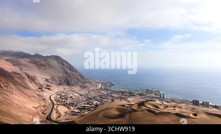 Einzigartiges und interessantes Landschaftsfoto der großen Hafenstadt Iquique, Chile. Erhöhter Blick auf die Stadt, die ein Hafen an der Pazifikküste und Wüste ist. Stockfoto