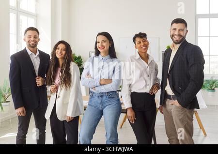 Verschiedene Gruppen glücklicher Profis stehen und posieren im modernen Büro und lächeln selbstbewusst Stockfoto