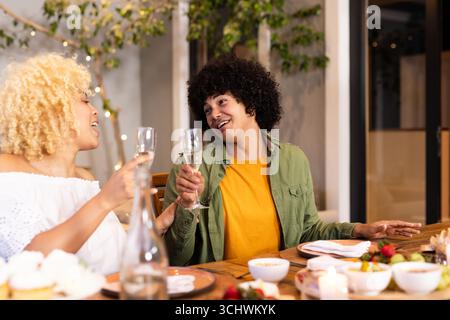 Mit Champagner feiern, multirassische Freunde auf der Dinnerparty, lächeln, reden, auf der Terrasse Stockfoto