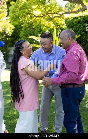 Im Garten lachen verschiedene Senioren zusammen und genießen sonniges Treffen im Freien Stockfoto