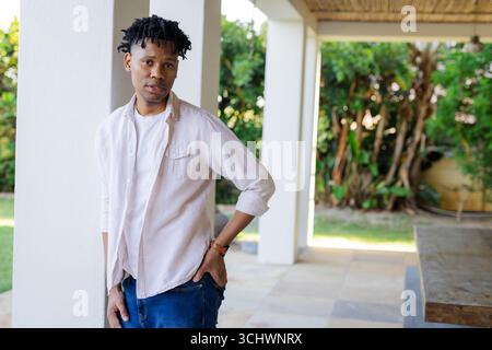 Junger Mann, der auf der Terrasse steht, nachdenklich aussieht und Entspannung im Freien genießt Stockfoto