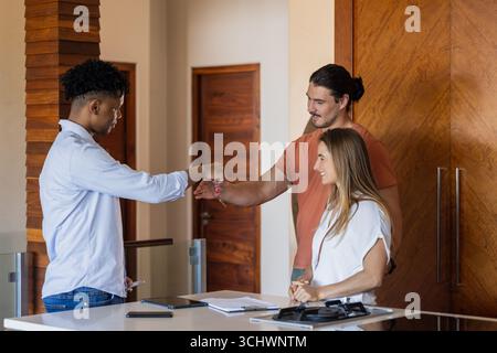 Verschiedene Freunde begrüßen mit Faustschlag im modernen Büro, lächeln und verbinden sich Stockfoto