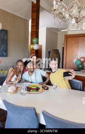 Freunde machen zu Hause Selfie, feiern mit Essen und Getränken, lächeln fröhlich Stockfoto
