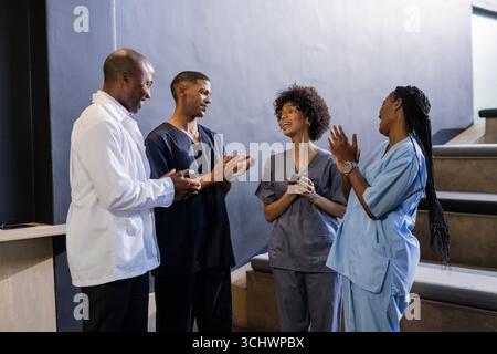 Im Krankenhausflur diskutieren Mediziner in Scrubs gemeinsam die Patientenversorgung Stockfoto