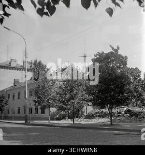 Eine Schwarzweißaufnahme aus dem Archiv, aufgenommen in Sloviansk in den 1960er Jahren Bankovska Straße, gepflastert mit Kopfsteinpflaster, während des Abrisses alter vorrevolutionärer Gebäude. Anstelle eines abgerissenen Hauses befindet sich ein leeres Grundstück und ein Haufen Bauschutt. Das Foto ist ein historisches Dokument, das die Rekonstruktion aus der Sowjetzeit und das sich verändernde historische Gesicht des Zentrums von Sloviansk feststellt Stockfoto
