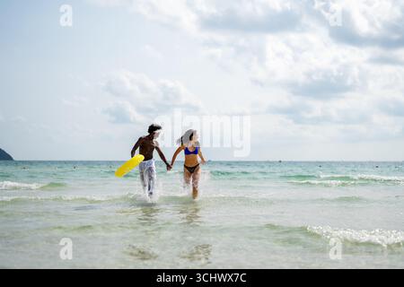 Interrassisches Paar, das einen romantischen Strandurlaub genießt und Liebe, Lachen und Zweisamkeit genießt Stockfoto