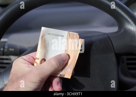 Person, die gefaltete Euro-Banknoten in einem Auto hält Stockfoto