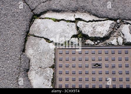 Zugangsabdeckung und gerissener Asphaltboden Stockfoto