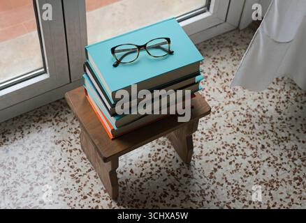 Stapel Bücher und Gläser auf dem Stuhl Stockfoto