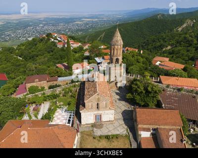 Historische Kirche mit Turm in einem Dorf umgeben von Bergen mit roten Ziegeldächern, Blick aus der Luft, Kirche St. George, St. George, Sighnaghi, Signagi Stockfoto