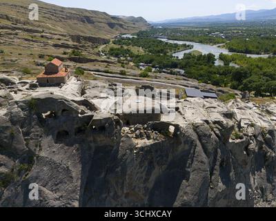 Historische Kirche auf felsiger Klippe mit Panoramablick auf Fluss und grüne Landschaft, aus der Luft, Höhlenstadt Uplistsikhe, Uplistsikhe, Fluss Kura oder Mtkvar Stockfoto