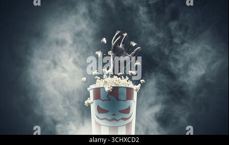 Gruselige Zombie-Hand aus einem Popcorn-Eimer: Horrorfilme und Halloween-Konzept Stockfoto