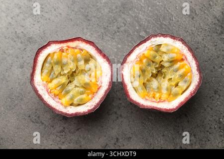 Hälften frischer Passionsfrucht auf grauem Tisch, flach gelegen Stockfoto