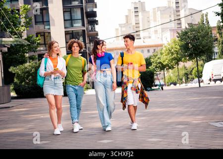Fröhliche junge Freunde, die an einem sonnigen Tag gemeinsam in der Stadt spazieren gehen und Spaß am Lebensstil widerspiegeln Stockfoto