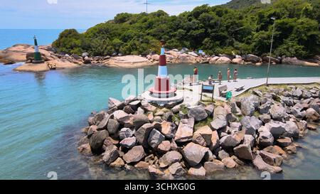 Aus der Vogelperspektive auf den Steg des Barra da Lagoa Beach Kanals mit einem kleinen Leuchtturm für Boote in Florianópolis, Santa Catarina, Brasilien Stockfoto