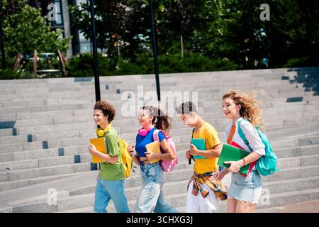 Glückliche Gruppe von verschiedenen jungen Studenten, die an einem sonnigen Tag im Freien gemeinsame Zeit genießen Stockfoto