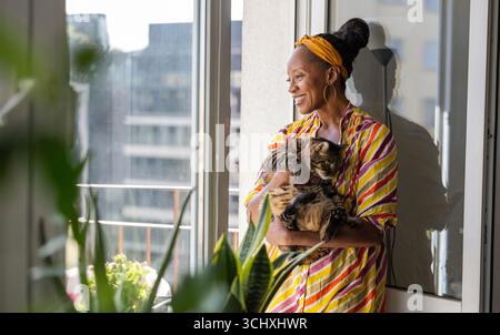 Porträt einer lächelnden Frau mit ihrer Katze zu Hause Stockfoto