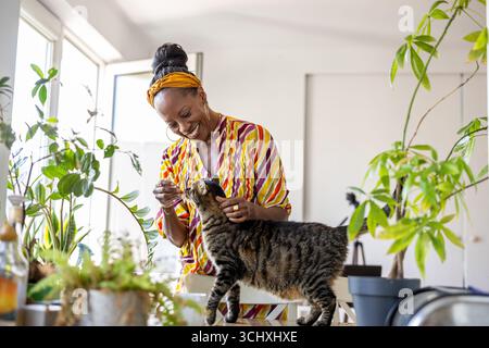 Porträt einer lächelnden Frau mit ihrer Katze zu Hause Stockfoto