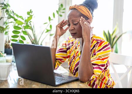 Porträt einer gestressten Frau mit Laptop zu Hause Stockfoto