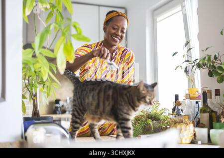 Porträt einer lächelnden Frau mit ihrer Katze zu Hause Stockfoto