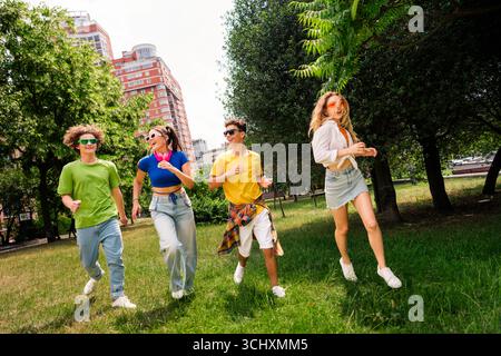 Eine Gruppe verschiedener Freunde, die einen sonnigen Tag im Freien in einer Parklandschaft mit Natur und urbanem Hintergrund genießen Stockfoto