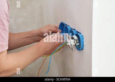 Elektriker, der neue Steckdosen in den Wandsteckdosen installiert Stockfoto