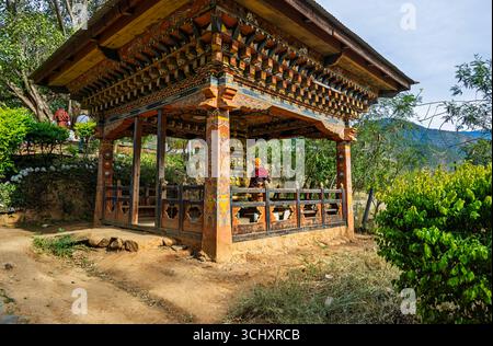 Gebetsmühle und Mönch in Chimi Lhakhang, dem Mad Mönch Tempel, in Teoprongchu Dorf bei Sopsokha, Lobesa Tal, Punakha Bezirk, Bhutan Stockfoto