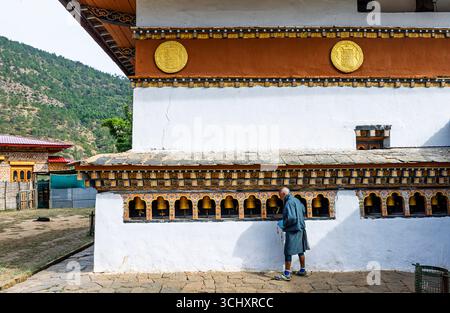 Ein Gläubiger spinnt Gebetswender in Chimi Lhakhang, dem Mad Mönch Tempel, Teoprongchu Dorf bei Sopsokha, Lobesa Tal, Punakha District, Bhutan Stockfoto