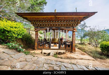 Gebetsmühle und Mönch in Chimi Lhakhang, dem Mad Mönch Tempel, in Teoprongchu Dorf bei Sopsokha, Lobesa Tal, Punakha Bezirk, Bhutan Stockfoto