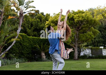 Junge, vielfältige Paare, die einen spielerischen Moment im Garten genießen, sich freudig und sorglos fühlen, Kopierraum Stockfoto