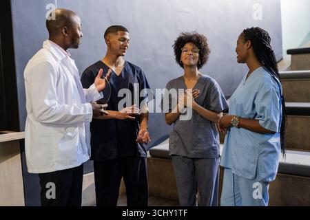 Im Krankenhaus, medizinische Fachkräfte tragen Peelings und Laborkittel, arbeiten zusammen Stockfoto