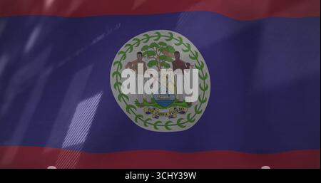 Flatternde Nationalflagge von Belize, die bei Tageslicht auf einem Fahnenmast fliegt, mit Wappendetails Stockfoto
