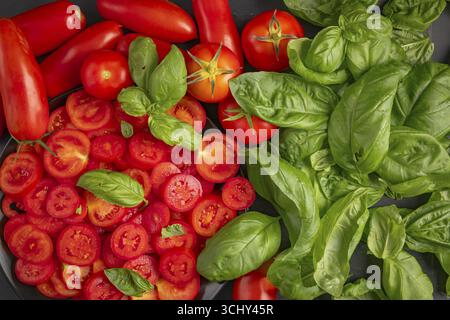 In Scheiben geschnittene und ganze Tomaten mit frischem Basilikum Stockfoto