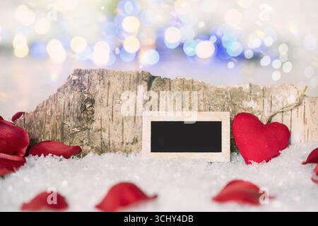 Kleiner Schiefer und rotes Herz im Schnee, komponiert Stockfoto