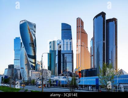 Flacher Blick auf moderne Business-Wolkenkratzer im Finanzviertel bei Sonnenuntergang. Reflektierende Wolkenkratzer, Bürogebäude vor blauem Himmel. Stockfoto