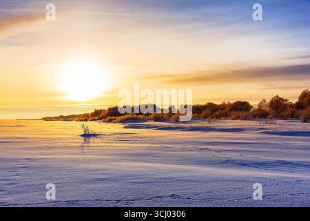 Malerischer Blick auf Sonnenuntergang und Schneefeld. Feld bedeckt mit Schnee in der kalten Wintersaison. Stockfoto