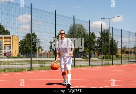 Moderne Frauen spielen im Sommer Basketball auf dem städtischen Straßengarten Stockfoto