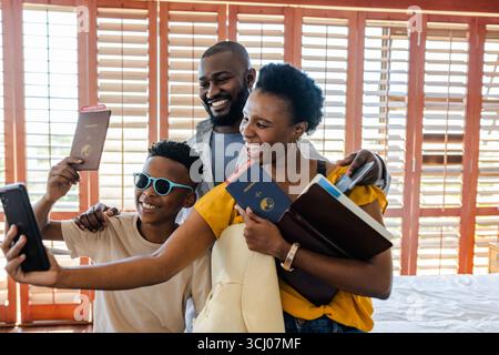 Familie macht Selfie mit Pässen, lächelt und bereitet sich auf Urlaubsabenteuer vor Stockfoto