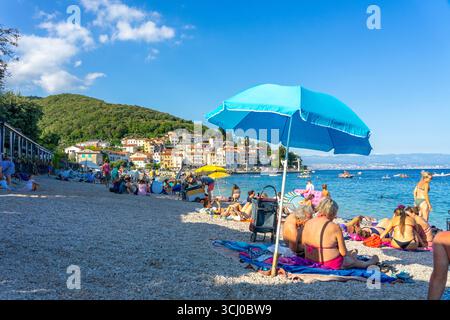 Moscenicka Draga, Kroatien - 08.28.2025: Überfüllter Strand mit wunderschönem klarem Wasser und Blick auf eine Stadt Stockfoto