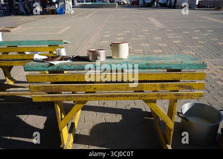 In Gelb und Türkis getragen, sitzt auf einem kretischen Platz ein Schulpult aus vergangener Zeit, ein einfaches und nostalgisches Relikt, das an eine ruhige Besinnung erinnert. Stockfoto