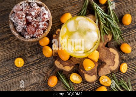 Orangensaft und frische Kumquat-Früchte auf einem Holztisch, köstlicher und frischer Orangensaft und frisches Kumquat-Obst neben einem Glas Stockfoto