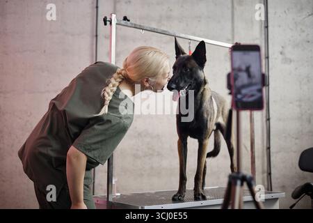 Kaukasische junge Erwachsene Frau, die liebevoll mit belgischem Schäferhund interagiert Stockfoto