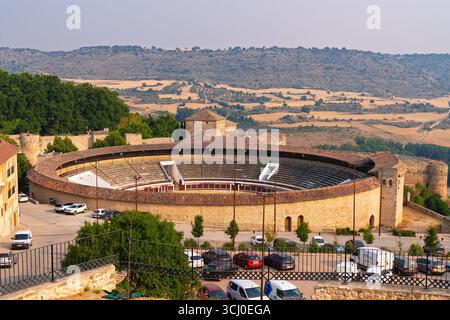 Brihuega, Spanien. August 2025. Die historische Stierkampfarena von Brihuega, ein prominentes Wahrzeichen, wird bei Sonnenuntergang mit sanften spanischen Hügeln gesehen Stockfoto
