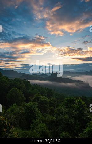 Aus der Vogelperspektive der Sonne über den Berggipfeln scheint durch das Tal. Bewölkter Himmel und umliegende Hügel unterstreichen das friedliche Ambiente Stockfoto