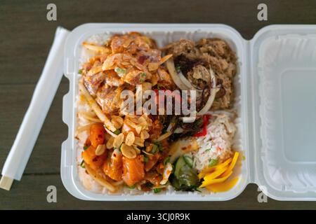 Blick von oben auf einen hawaiianischen Poke-Mittagstisch mit scharfem Aahi, Lachs, Kalua-Schweinefleisch, Krabbensalat und eingelegtem Gemüse. Vermarktungskonzept für Rohkost Stockfoto