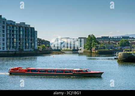 Ein Touristenboot auf dem Liffey mit dem Fluss Dodder, der Ringsend-Brücke und dem Aviva-Stadion in der Ferne. Dublin, Irland. Stockfoto