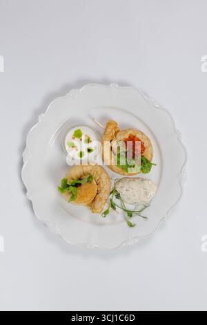 Elegantes Servieren von Gourmet-Pfannkuchen mit rotem Kaviar, frischem Salat, Cremesauce und Kräutern auf einem weißen Teller für das Restaurantmenü. Stockfoto